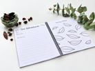 Chilli Keepsakes spiral dog memory book open to ‘Our Adventures’ and ‘Our Day in Photos’ pages, with lined writing space and leaf illustrations, styled with eucalyptus.
